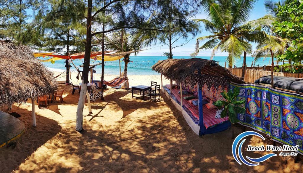 阿鲁甘湾Beach Wave Hotel的一个带椅子和遮阳伞的海滩的度假胜地