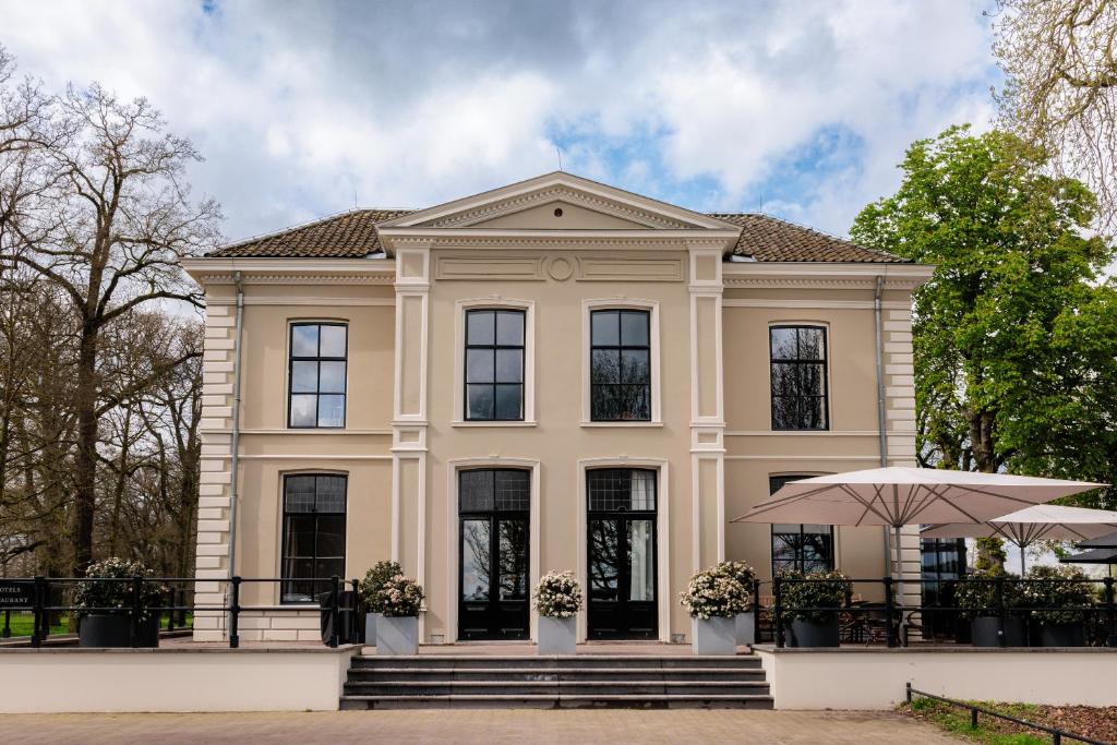 迪温特Pillows Luxury Boutique Hotel aan de IJssel的一间设有黑窗和遮阳伞的大型棕褐色房子