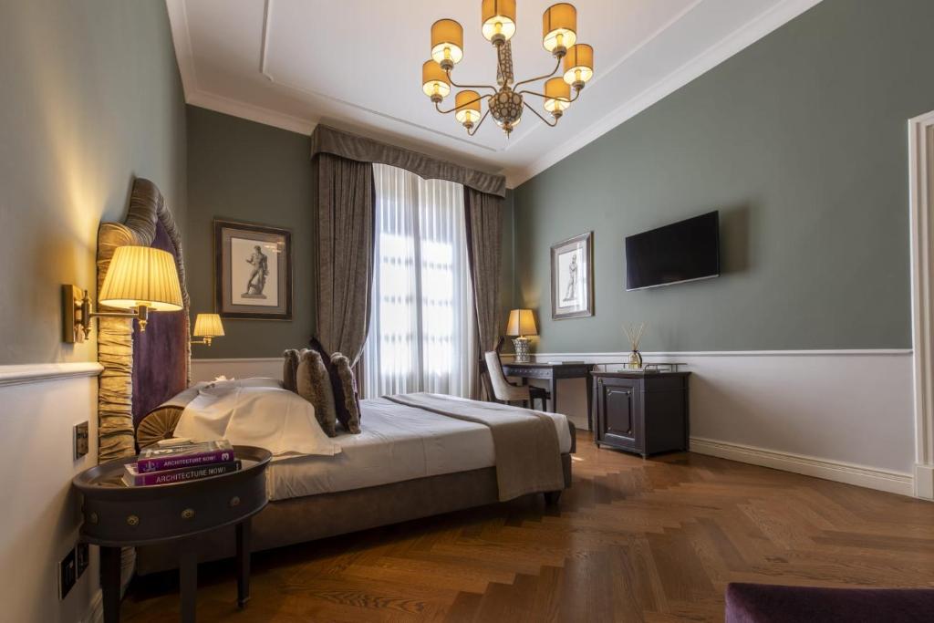 佛罗伦萨帕拉佐罗塞利切克尼酒店的一间卧室配有一张床、一张书桌和一个吊灯。