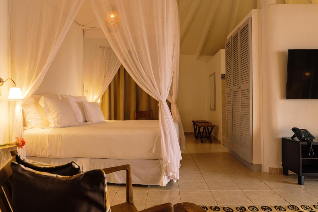 Principe普林西比波乌波乌酒店的一间卧室配有一张带窗帘的床和电视。