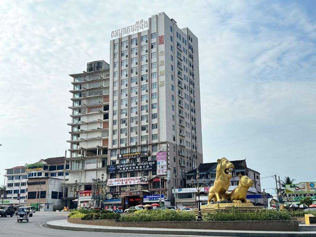 西哈努克怡程酒店ECHENG HOTEL的一座高大的建筑,前面有狮子雕像