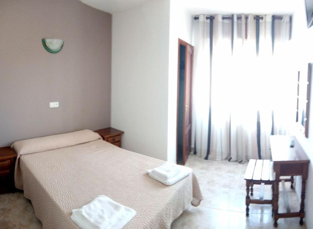 阿罗萨新镇HOTEL LAGO的一间卧室配有一张床、一张书桌和一个窗户。