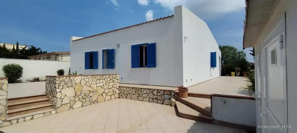 特拉帕尼2 bedrooms house at Marsala 250 m away from the beach with sea view and furnished garden的白色的房子,设有蓝色的窗户和石墙