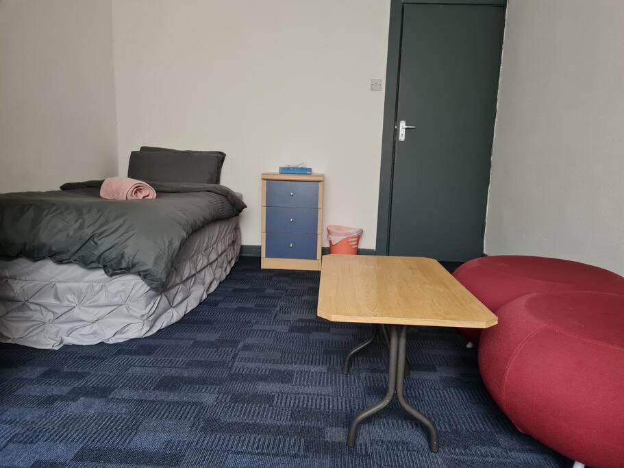 凯格沃思Room near East Midland Airport 7的一间设有床、桌子和红色沙发的房间