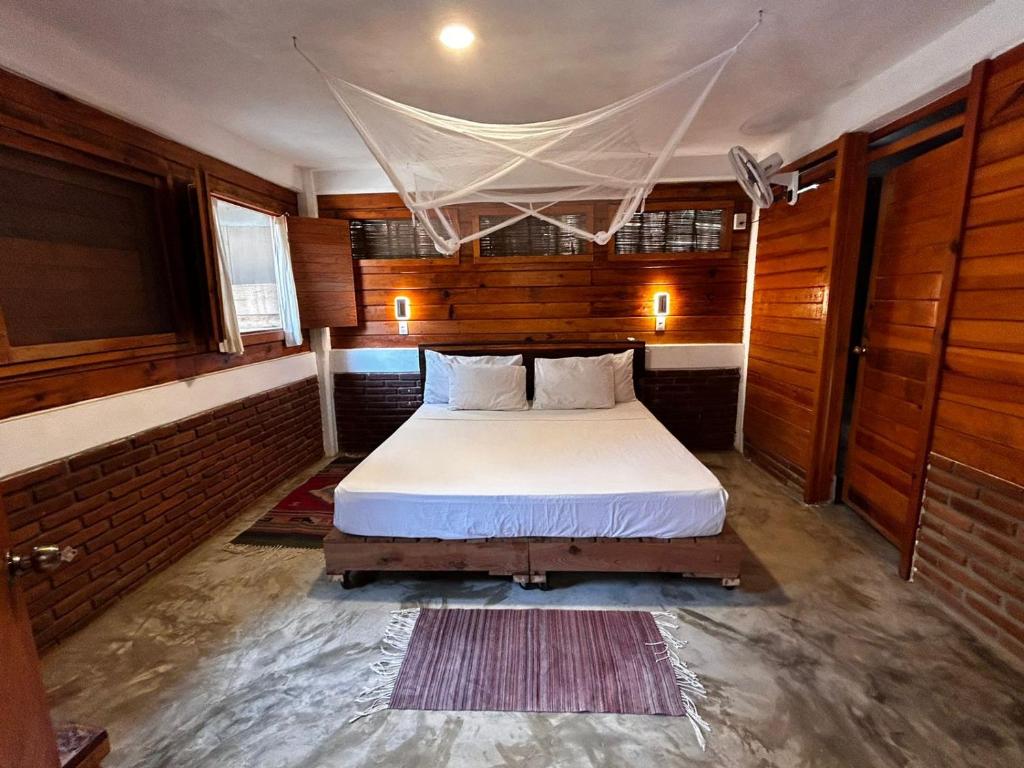 马祖特Casa Gaviota的卧室配有一张床铺,位于带木墙的房间内
