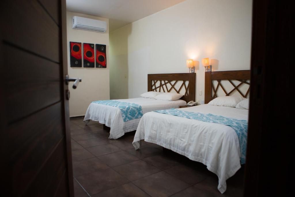 马德罗城Hotel Tres Soles的一间设有两张带白色床单的床的房间