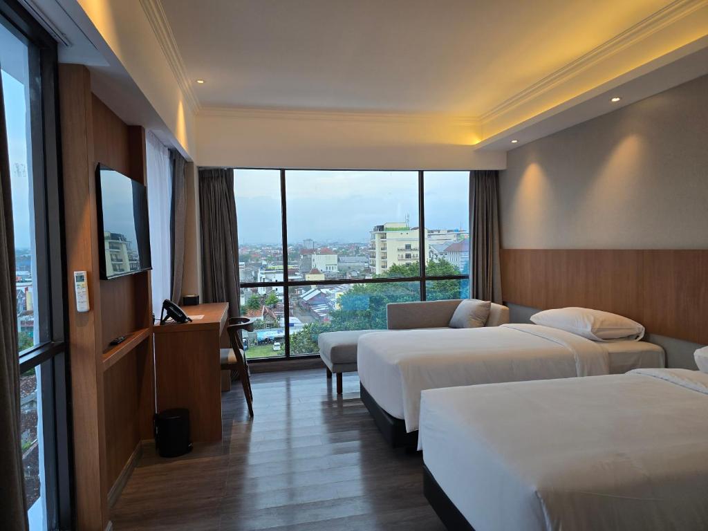 日惹The Malioboro Hotel & Conference Center的酒店客房设有两张床和大窗户。