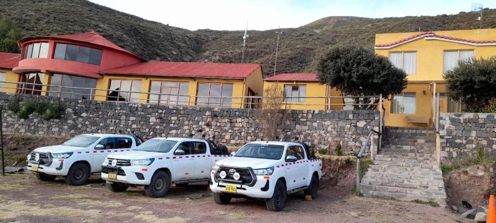 奇瓦伊Hotel Mirador del Colca Lodge的两辆白色卡车停在石墙前