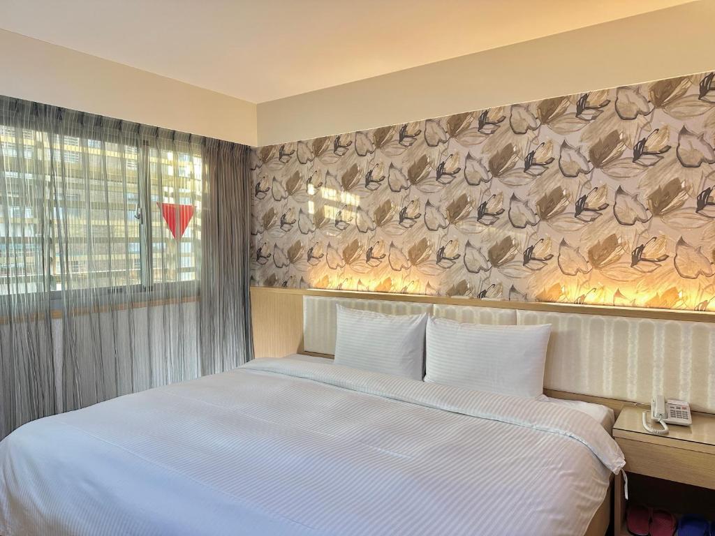 台中市美之旅商务饭店的卧室配有白色的床和带羽毛的墙壁。