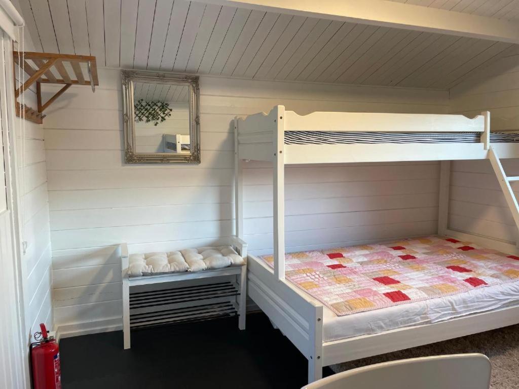 奥斯陆Nice Apartment with1 bedroom Separate living room with a sofa bed and a tiny kitchen a bathroom located in Nordstrand near by the Sea for 3 guests with a garden and grill 5 extra guests with extra cost in the cabin with sea view just outside the apartment的客房设有两张双层床和镜子