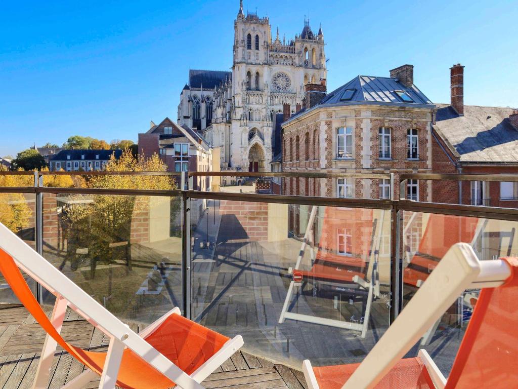 亚眠亚眠教堂美居酒店的阳台设有两把椅子,享有大楼的景色