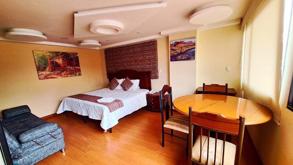 帕斯托Hotel Xilon Resort Plaza的一间卧室配有一张床铺和一张桌子,还有一间用餐室