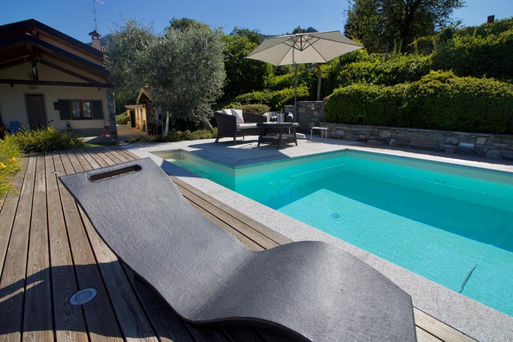 卡斯泰尔韦卡纳Oasi di Castelveccana Apt Pool and View的一个带桌子和遮阳伞的游泳池