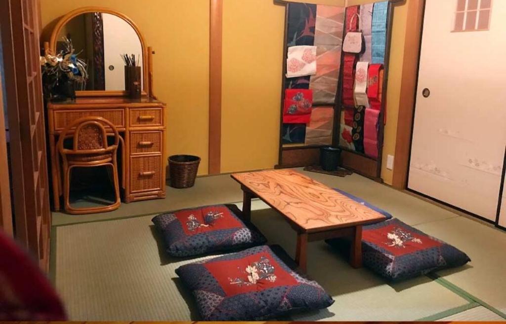 Shimmachidōri百合の家的客厅配有桌子和两把脚凳