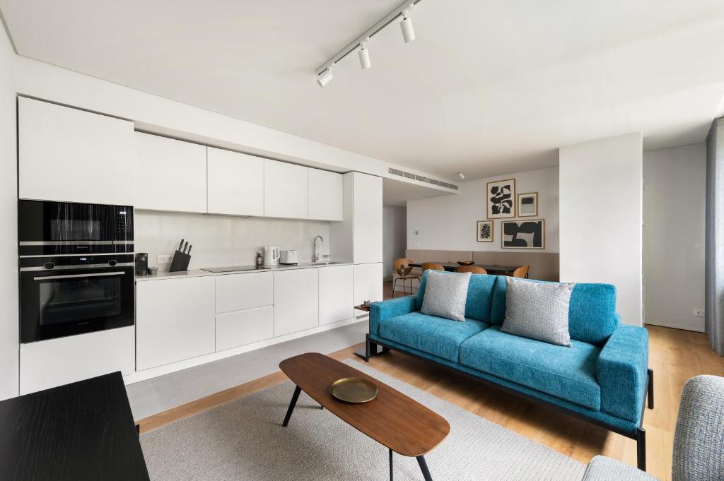 里斯本Mirabilis Apartments - LX Living的一间带蓝色沙发的客厅和一间厨房