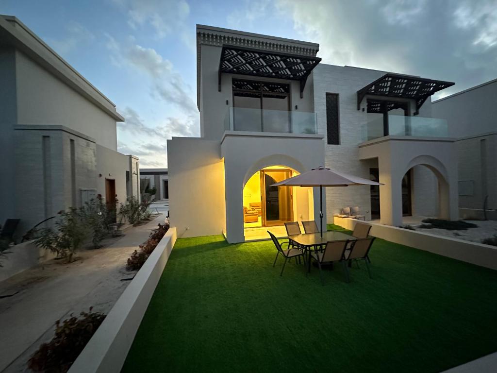 塞拉莱Wonderful Ground Studio - Hawana Salalah Resort的草坪上带桌椅的房子