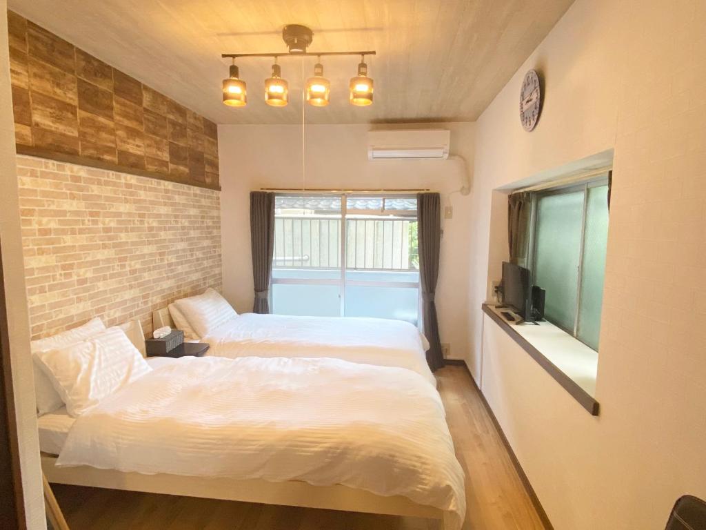 福冈Rapport Kukomae 207的一间卧室设有两张床和砖墙
