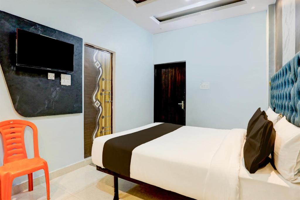 瓦拉纳西Super OYO Flagship SHIVA VALLEY HOTEL的一间卧室配有一张床、一把椅子和电视。