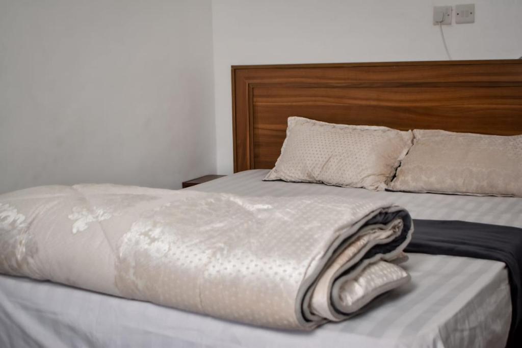 KiambuMella homes limuru的一张带木制床头板和毛巾的床