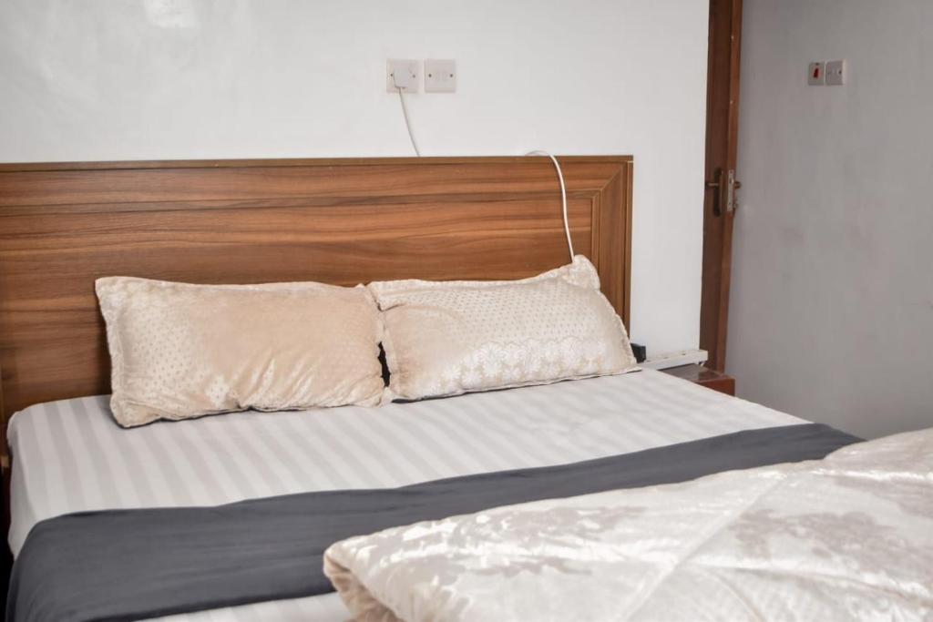 LimuruMella homes limuru的一张带木制床头板和两个枕头的床