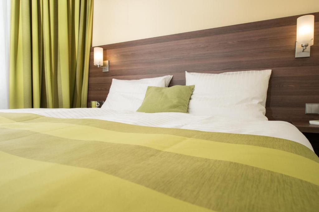 美因河畔法兰克福Goethe Conference Hotel by Trip Inn的一张配有白色床单和绿色枕头的大床