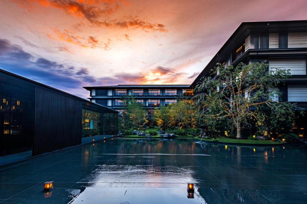 京都HOTEL THE MITSUI KYOTO, a Luxury Collection Hotel & Spa的一座享有日落美景的建筑前的游泳池