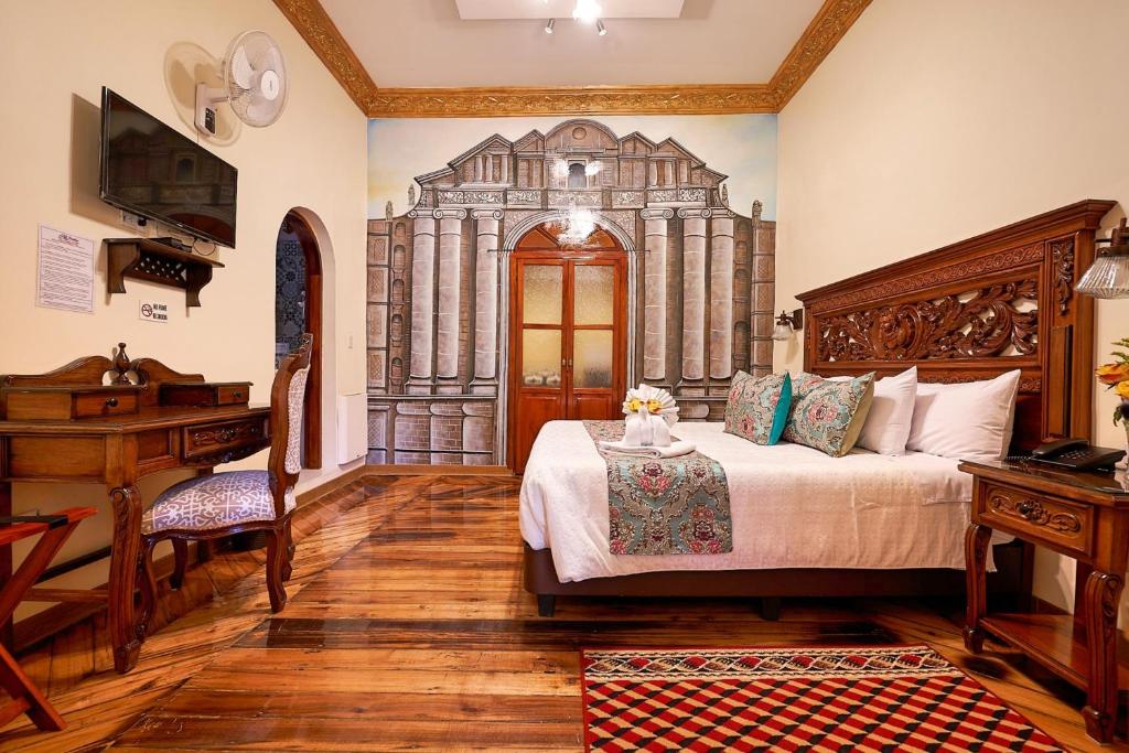 基多Hotel La Basílica Quito的一间卧室配有一张大床和一张书桌