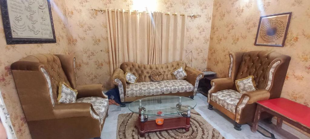 卡拉奇Maymar Holiday Home的客厅配有两把椅子和一张玻璃桌