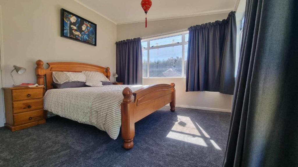 帕拉帕拉乌穆135 On Seaview Parpaparaumu Beach的一间卧室设有一张木床和一个窗户。