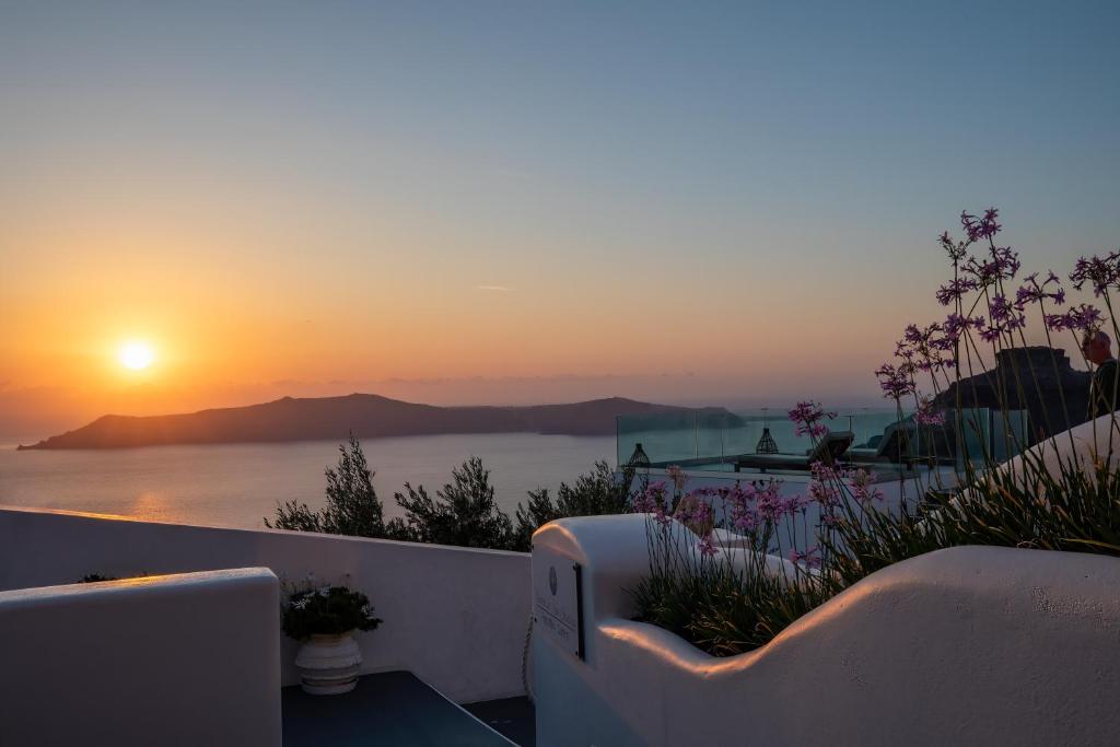 菲罗斯特法尼Santorini View Studios - Firostefani Caldera的鲜花阳台享有日落美景