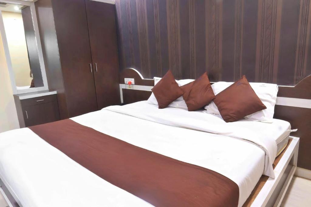 博帕尔HOTEL R K PALACE的卧室配有带棕色枕头的大型白色床