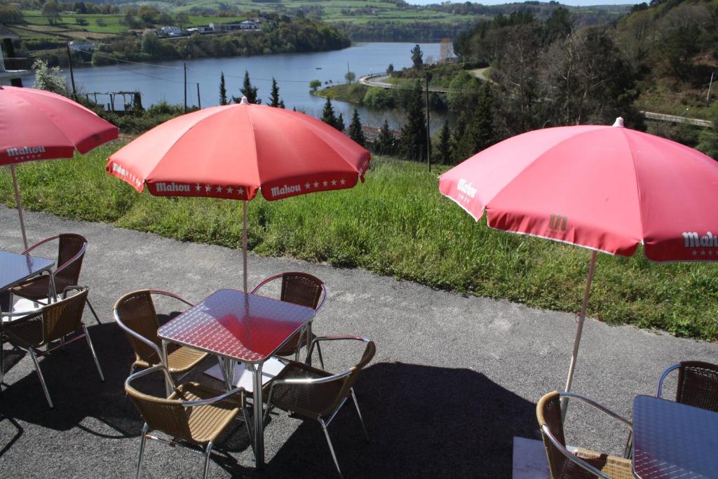 波尔托马林Albergue Ferramenteiro的一张桌子和椅子,上面有红伞和湖泊