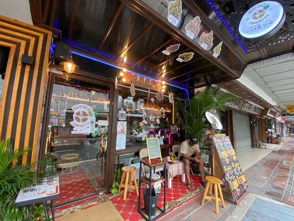 芭堤雅市中心Happiness Community Wake & Bake Hostel - Rooftop Bar & Bistro的坐在餐厅外桌子上的男人