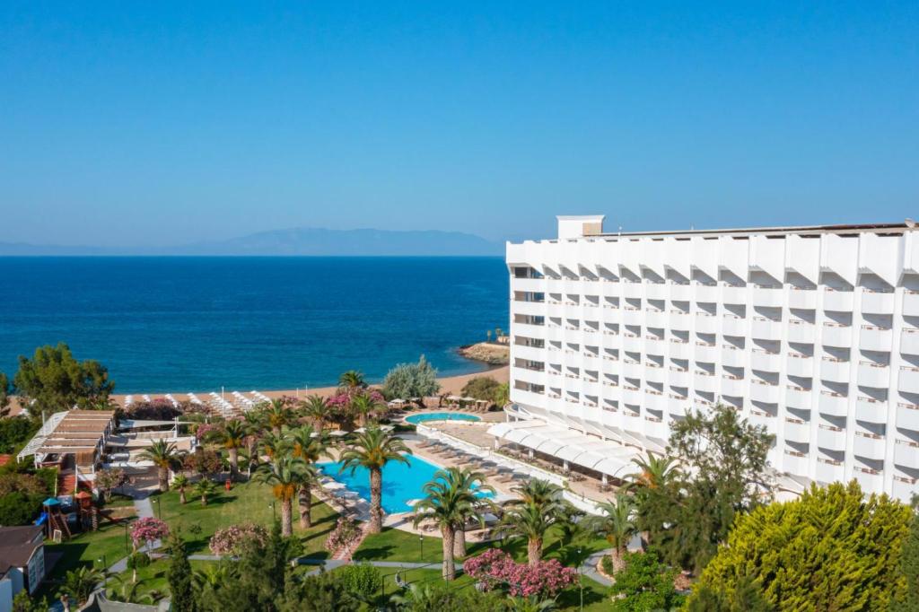 伊兹密尔Club Beyy Resort Hotel - Ultra All Inclusive的背景是一座带游泳池和大海的酒店