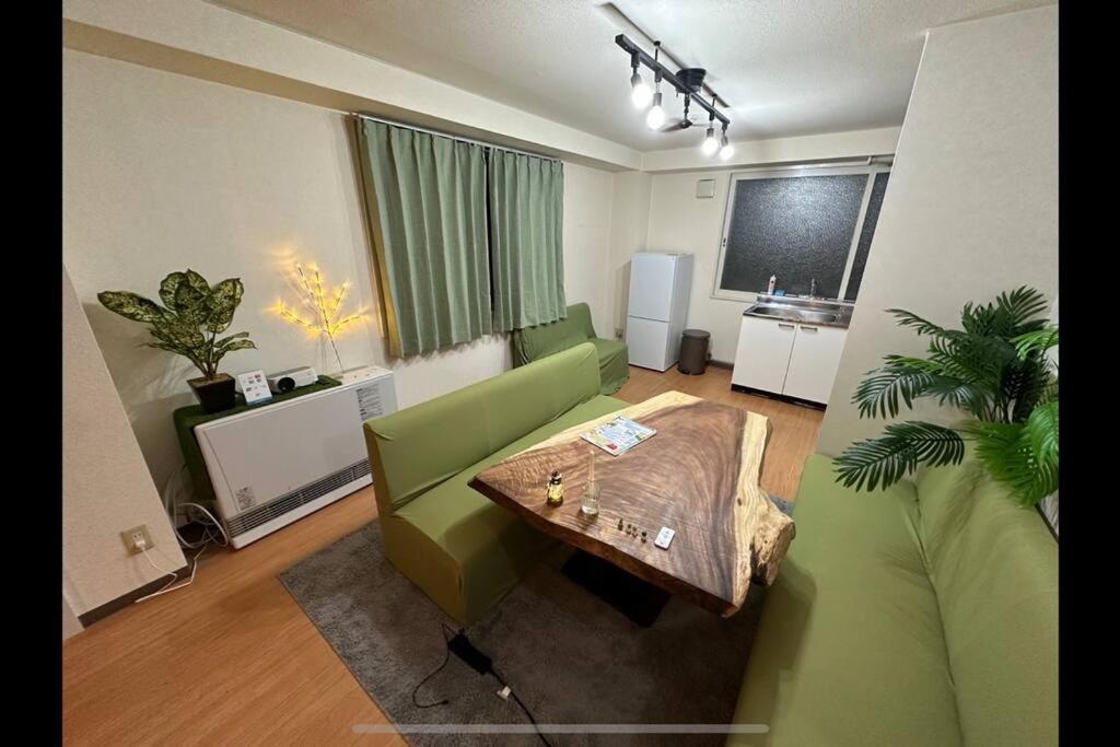 札幌Monster lodge 札幌的客厅配有绿色沙发和桌子