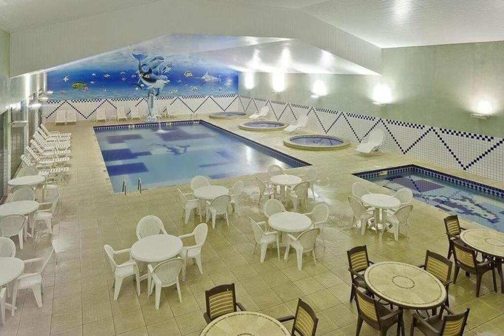 Represa CapivariApartamento completo em Resort的一个带桌椅的游泳池以及一座游泳池