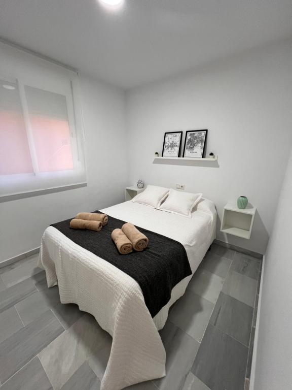 卡马斯Apartamento Jardín de Atalaya的一间白色卧室,床上配有2条毛巾