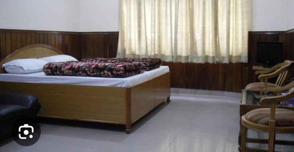巴德里纳特OM Kutir Badrinath Dham的一间卧室配有一张床和两把椅子