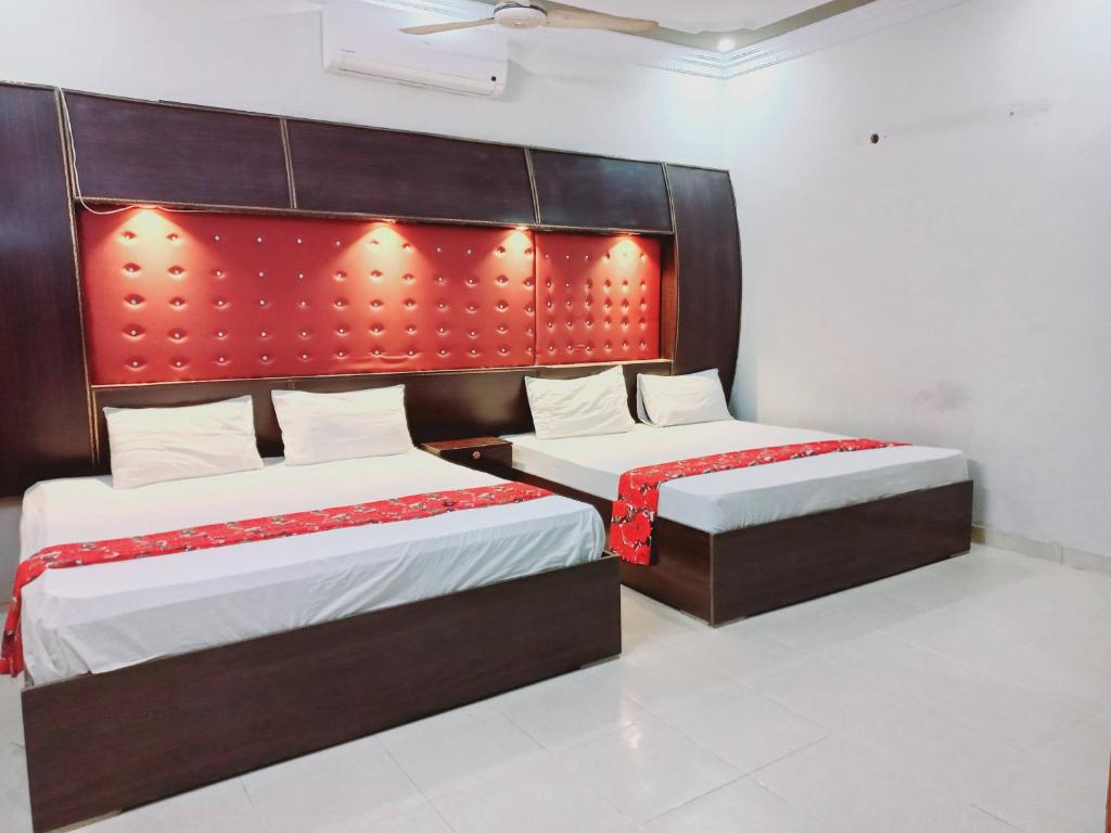 卡拉奇Rose Palace Guest House的一间卧室配有两张带红色床头板的床