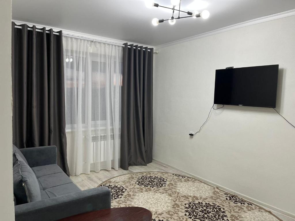 乌拉尔斯克2х комнатная квартира с кодовым замком的客厅配有沙发和墙上的电视