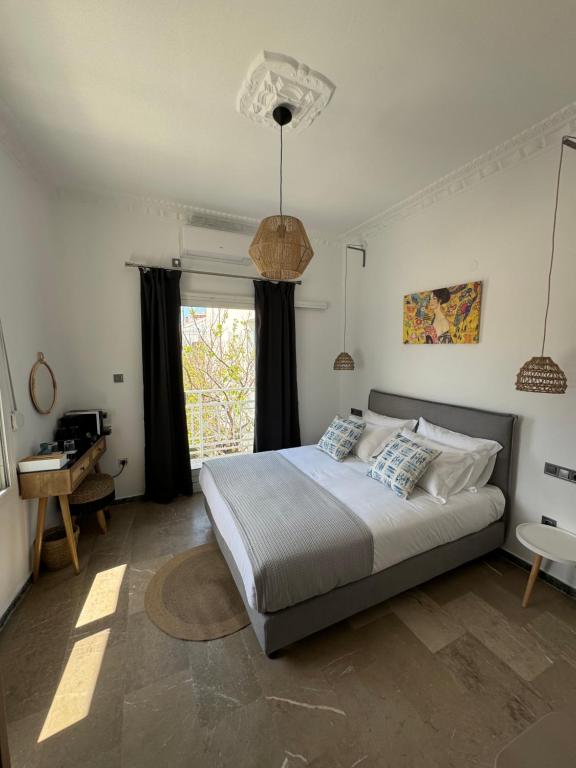 毕达哥利翁Blue Sardines的一间卧室配有一张床、一张书桌和一个窗户。