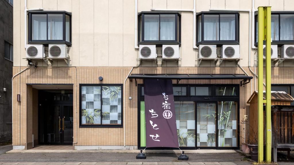 鹿角Tabist Oyado Chitose的一座带窗户的建筑,前面有一个横幅