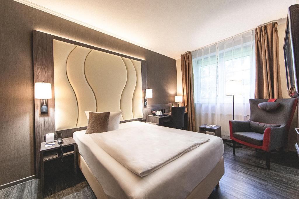诺德施泰特Best Western Hotel Schmoeker-Hof的配有一张床和一把椅子的酒店客房