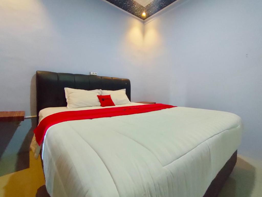 WatesRedDoorz Syariah Near Stasiun Wates的卧室配有一张大白色床和红色毯子