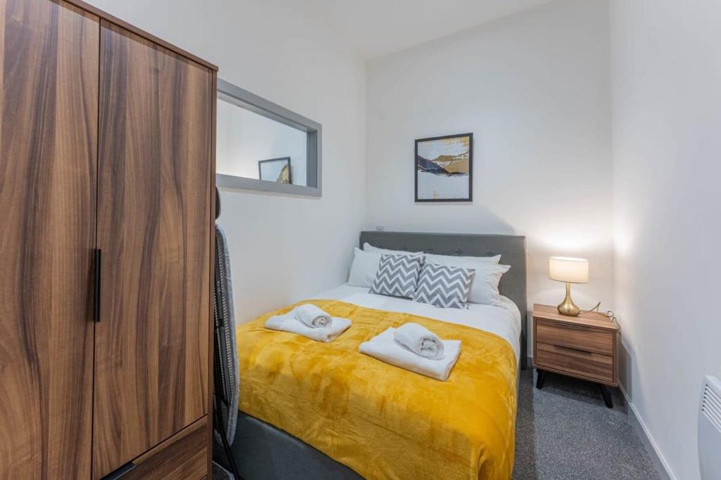 布赖尔利希尔Modern 1 Bedroom Apartment in Dudley的一间卧室配有一张带黄床单和木柜的床。