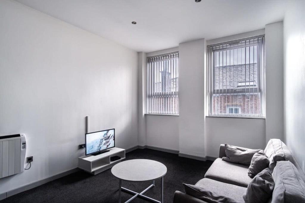 布莱克本Lovely 1 Bed Apartment in Central Blackburn的带沙发和电视的客厅以及2扇窗户。