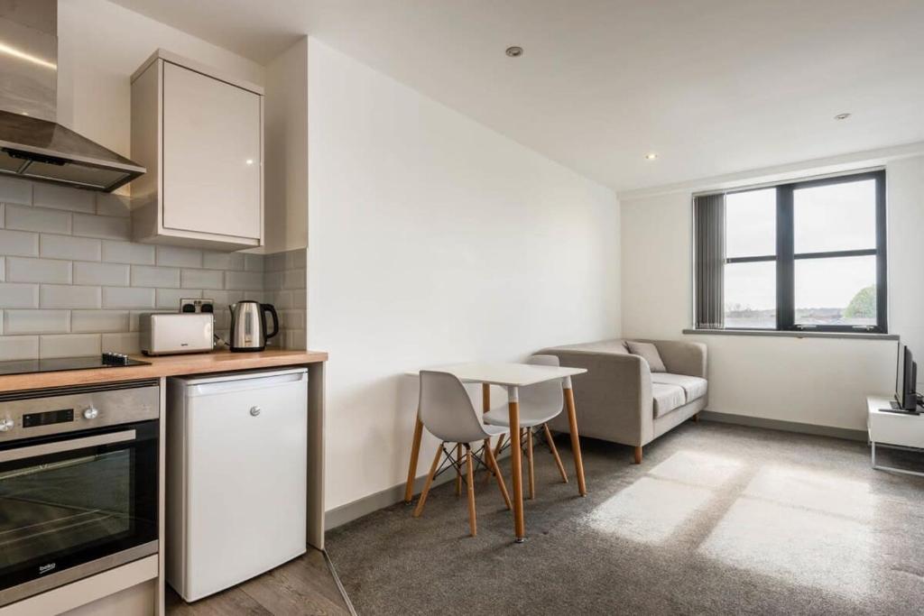 巴恩斯利Modern 1 Bedroom Budget Apartment in Barnsley的厨房以及带桌子和沙发的客厅。