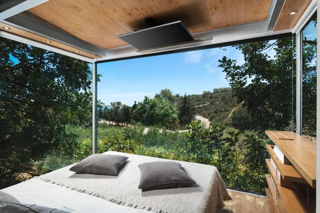 LoutrákionLuxury TreeHouse - A breath away from the beach的一间卧室设有一张床和一个大型玻璃窗