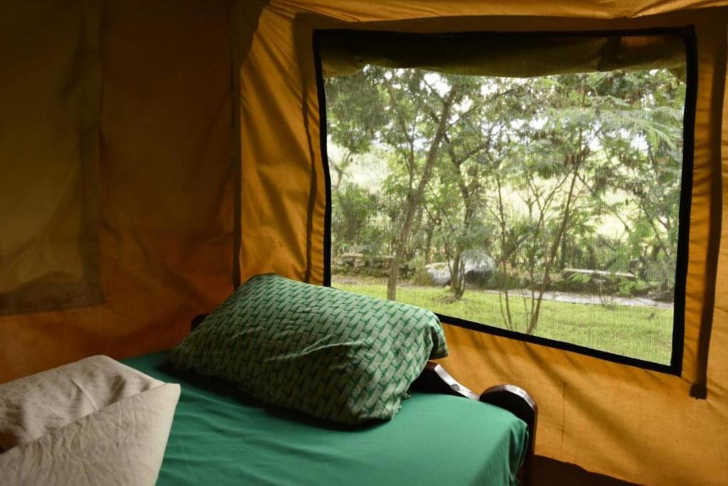 NyakinamaRoom in BB - Red Rocks Rwanda - Safari Tent Twin的帐篷内的枕头,床上有窗