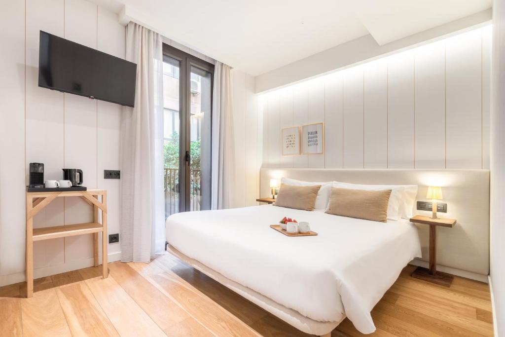 巴塞罗那Casa Bella Gracia by Aspasios的白色卧室设有一张大床和电视。